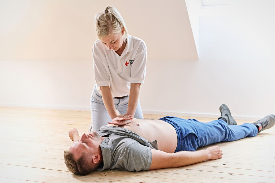 Eine Frau führt bei einem am Boden liegenden Mann die Herzdruckmassage durch (Übungsbild)